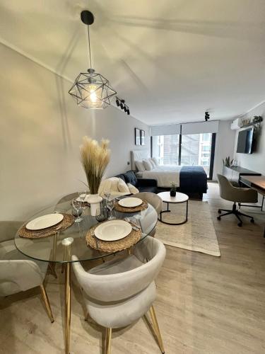 a living room with a glass table and chairs at Nuevo y lujoso apartamento full a pasos de Clínica Las Condes in Santiago