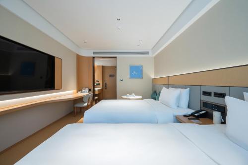 北京市にあるJI Hotel Beijing Xizhimen Jiaotong Universityの大きなベッドと薄型テレビがあるホテルの部屋