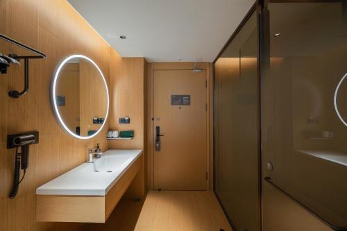 北京市にあるJI Hotel Beijing Xizhimen Jiaotong Universityの洗面台、鏡、シャワー付きのバスルーム