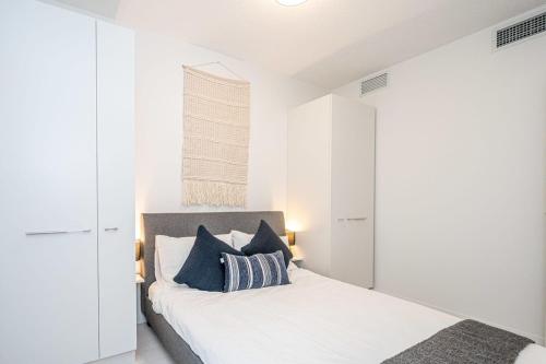 Un dormitorio blanco con una cama con almohadas azules. en Modern Suite by Olympic Village SkyTrain Sleeps 3, en Vancouver