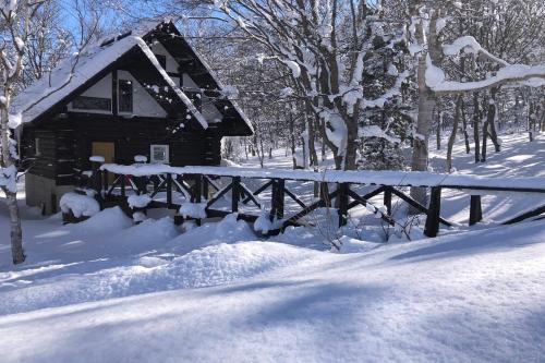 a log cabin in the snow with a fence at Appi Ski Chalet in Hachimantai