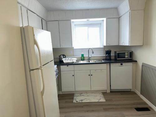 a kitchen with a white refrigerator and a sink at Joyful Home Regina in Regina