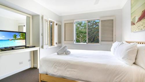 a white bedroom with a large bed and windows at Whitesands 501 in Forster