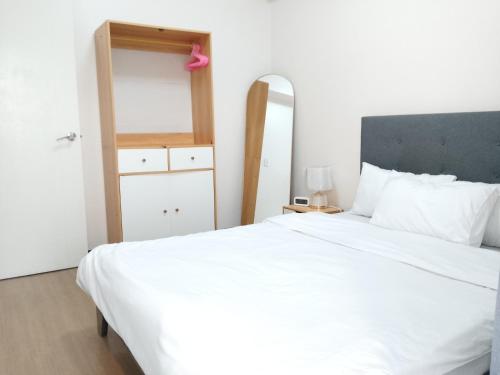 a bedroom with a large white bed and a mirror at Traveler Residence by Celandine in Manila
