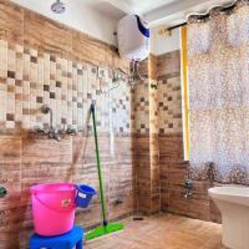 a bathroom with a pink bucket and a shower at Green Tara Mud House by StayApart in Kaza
