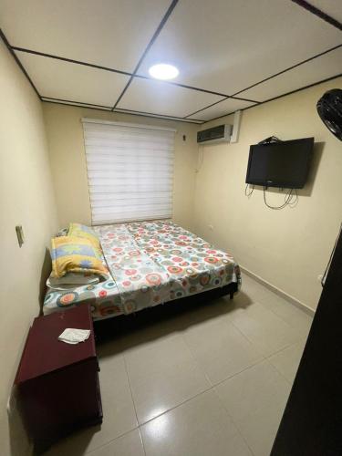 a small room with a bed and a tv at Casa Fenix in Dibulla