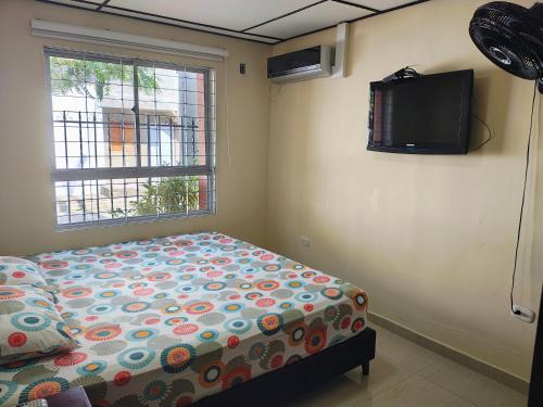 a bedroom with a bed and a tv on the wall at Casa Fenix in Dibulla