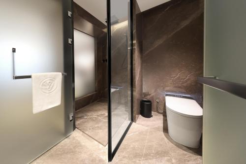 a bathroom with a toilet and a glass shower door at Guangzhou Huayu Wanfu Hotel-Free Shuttle Bus to Canton Fair Complex During Canton Fair Period in Guangzhou