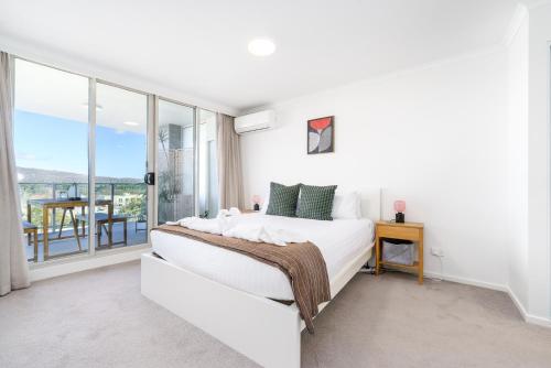 a white bedroom with a bed and a balcony at Modern 2BR Balcony with Views and Close to City - Hosted by Canstay in Braddon