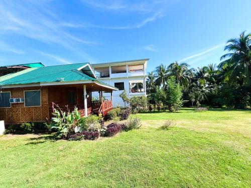 a house with a green roof on a grass field at Taylors Plantacion Resort- Grande Second Floor in Catarman