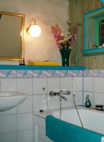 a bathroom with a sink and a tub with a vase of flowers at Annehelenes B&B in Bergen