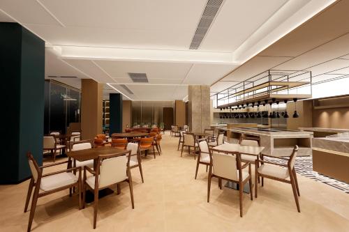 a restaurant with tables and chairs and a bar at Guangzhou Huayu Wanfu Hotel-Free Shuttle Bus to Canton Fair Complex During Canton Fair Period in Guangzhou