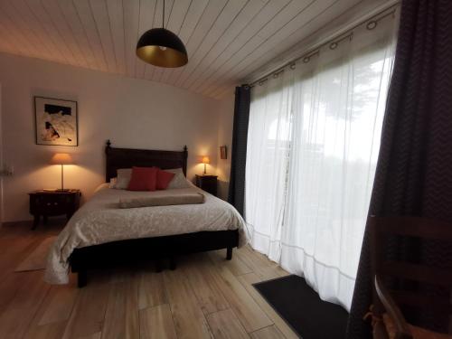 a bedroom with a bed and a large window at Le moulin de La Retardière in Orvault