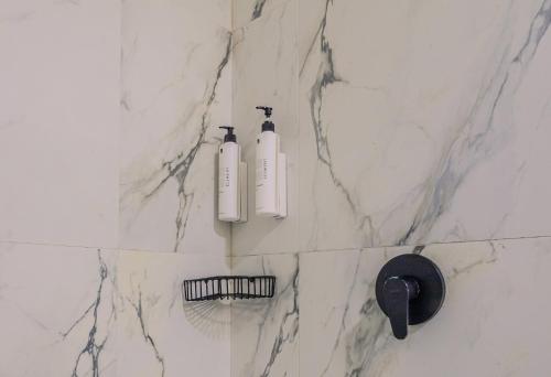 a bathroom with two shampoo bottles on a marble wall at Soy Local Parque La 93 in Bogotá