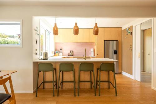 a kitchen with a island with four bar stools at Kiwi Street Retreat in Waiheke Island