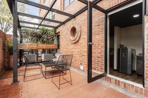 an outdoor patio with chairs and a brick wall at Soy Local Parque La 93 in Bogotá