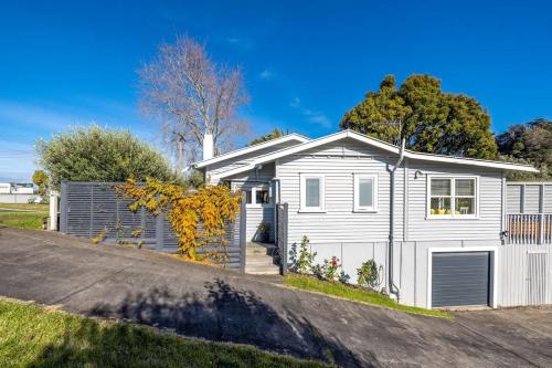 une maison blanche avec un garage dans une rue dans l'établissement Driftwood Cottage, à Waiheke Island