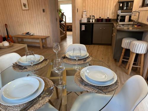 a glass table with plates and wine glasses on it at Casa Manzano ideal para Familias in Puerto Varas