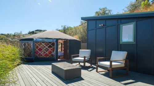 a gazebo with two chairs and a bench on a deck at Awaawa Yurts - Rangi in Waiheke Island