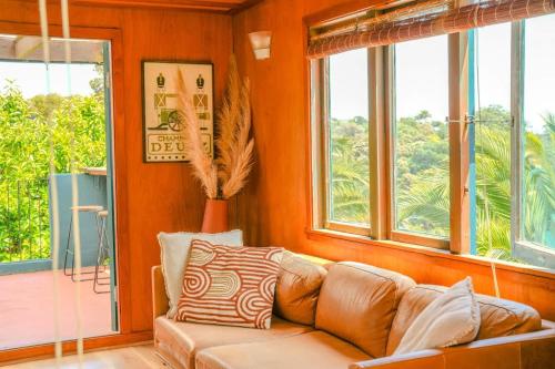 a living room with a brown couch and windows at Casa Del Mar in Waiheke Island