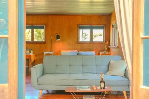 a living room with a blue couch and a table at Casa Del Mar in Waiheke Island