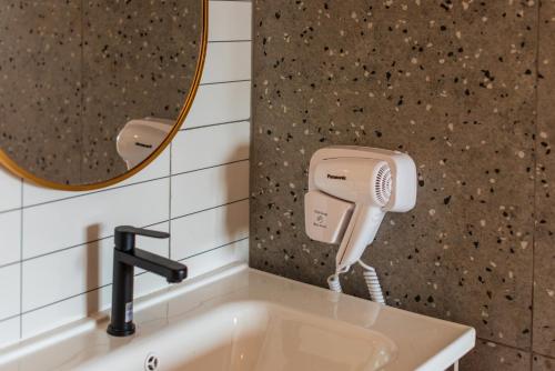 a bathroom sink with a hair dryer and a mirror at The Moment Hotel in Ban Bang Khan
