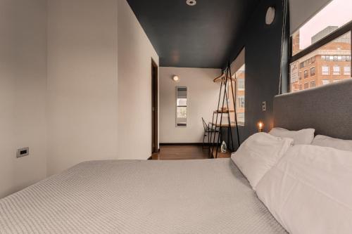 a bedroom with a white bed and a large window at Soy Local Parque La 93 in Bogotá