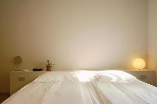 a bedroom with a white bed with a lamp on it at Pyoseon Mansion in Seogwipo