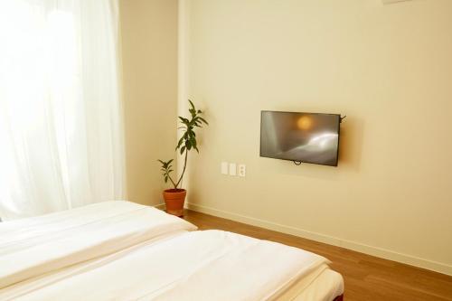 a room with two beds and a tv on the wall at Pyoseon Mansion in Seogwipo