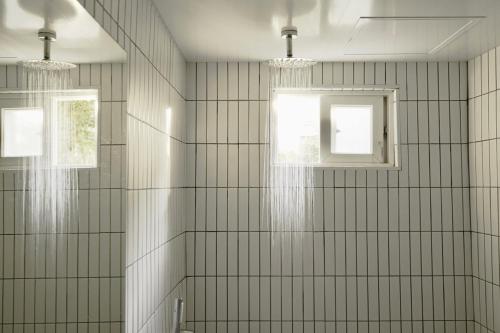 a bathroom with two windows and a white tiled wall at Pyoseon Mansion in Seogwipo