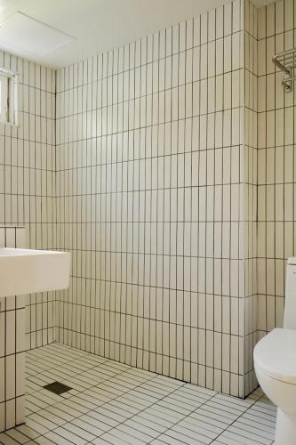 a white tiled bathroom with a sink and a toilet at Pyoseon Mansion in Seogwipo