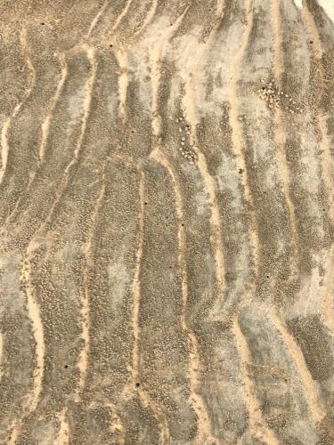 a field of sand with tire tracks in it at Pyoseon Mansion in Seogwipo