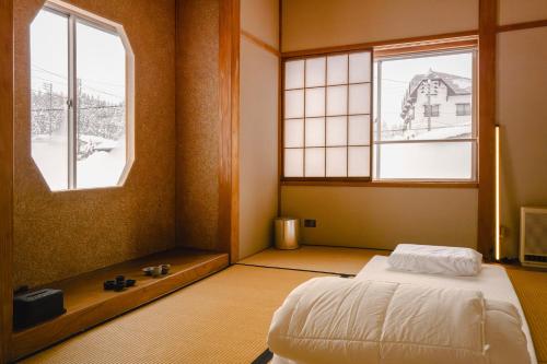 a bedroom with a bed and two windows at SLEEEP JP Myoko in Myoko