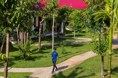 a person walking down a path through a park at Sala Siem Reap Resort in Siem Reap