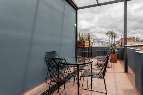 a balcony with a glass table and chairs at Soy Local Parque La 93 in Bogotá