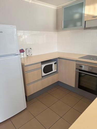 a kitchen with a white refrigerator and a microwave at Rydges Mount Panorama Bathurst in Bathurst