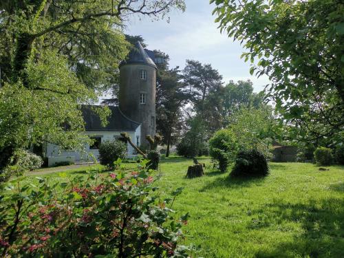 an old house in a field of grass with trees at Le moulin de La Retardière in Orvault