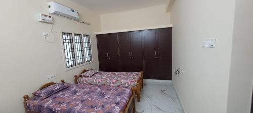 a bedroom with two beds and a window and a door at ELCI Residence PG luxury womens hostel Tambaram in Chennai