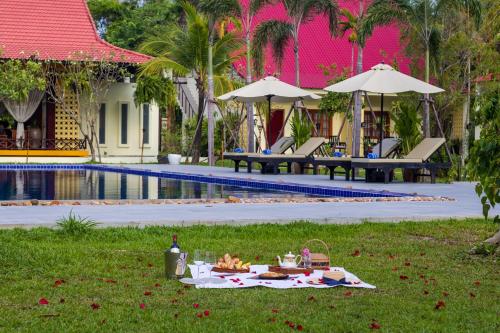 a picnic in the grass next to a pool at Sala Siem Reap Resort in Siem Reap
