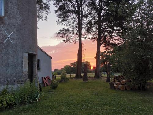 a sunset behind a building with trees in a yard at Le moulin de La Retardière in Orvault