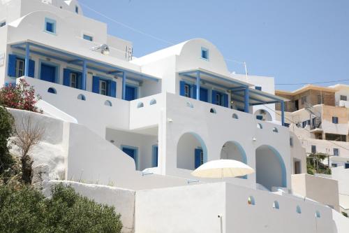 een wit huis met blauwe ramen en een witte paraplu bij Panselinos in Anafi