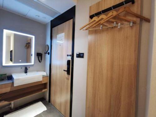 a bathroom with a wooden door and a sink at Green Tree Inn Express Shanghai Bund Yuyuan Xiaonanmen Metro Station in Shanghai