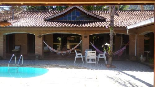 una casa con mesa y sillas y una piscina en Pousada Na Praia Ubatuba, en Ubatuba