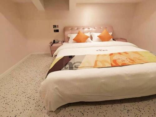 a bedroom with a large white bed with orange pillows at Shell Hotel Shanghai Jinshan Wanda Plaza in Nanhui