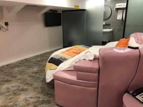 a room with a bed and a pink chair in it at Shell Hotel Shanghai Jinshan Wanda Plaza in Nanhui