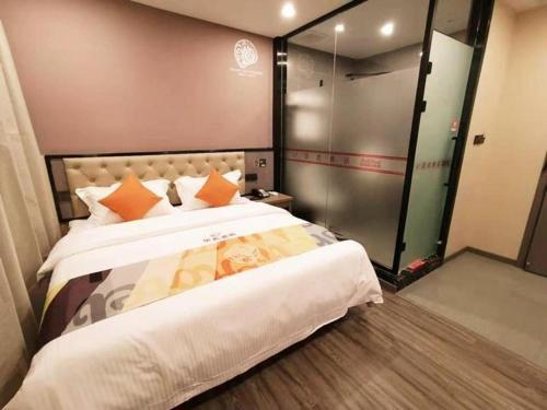 a bedroom with a large bed and a glass shower at Shell Hotel Shanghai Jinshan Wanda Plaza in Nanhui