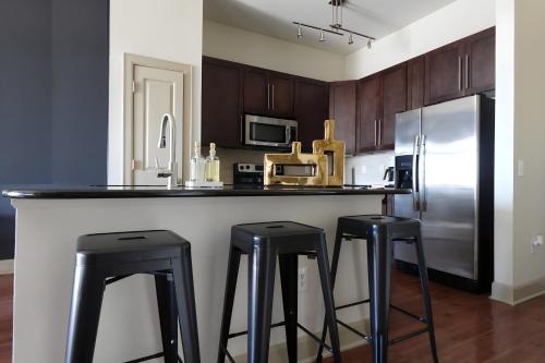 a kitchen with a counter with two stools and a refrigerator at The Downtown Nook A Cozy Urban Escape in Houston