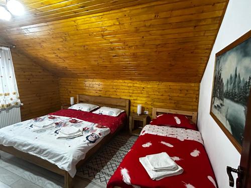 two beds in a small room with wooden ceilings at Cabana Boema in Rausor
