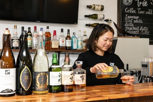 a woman sitting at a bar with a drink at White Tree Lodge Madarao Tangram in Shinano