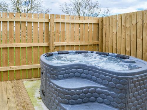 a hot tub in front of a wooden fence at Oxley Cottage in Orby